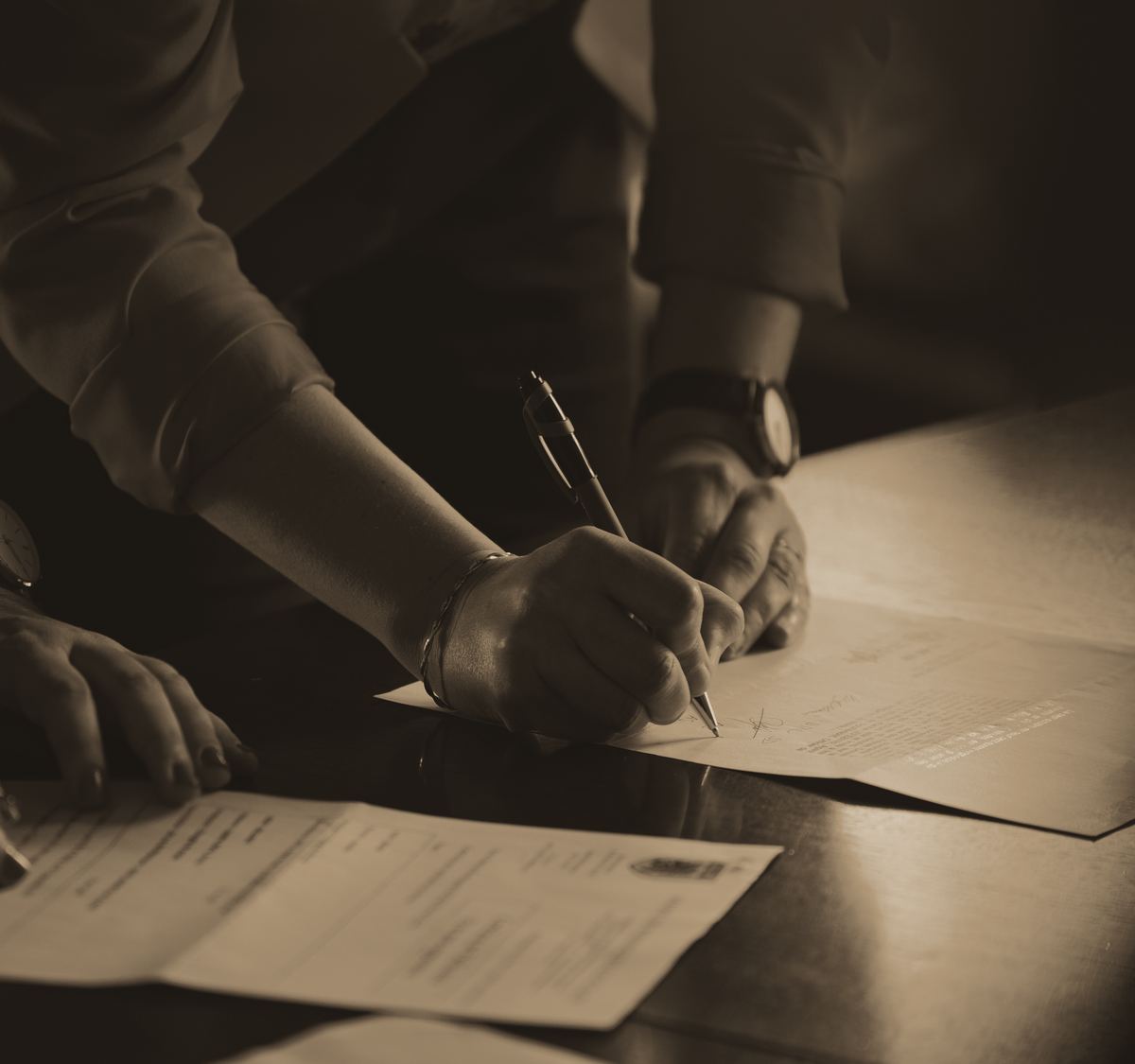 Manos que firman un documento sobre un escritorio